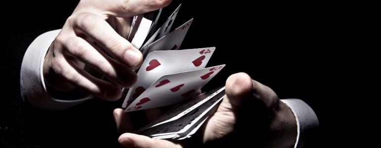 Magician shuffling the cards in a cool way under the spotlight Magician shuffling the cards in a cool way under the spotlight