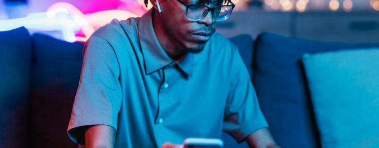 Man holding smartphone and watching at laptop Man holding smartphone and watching at laptop