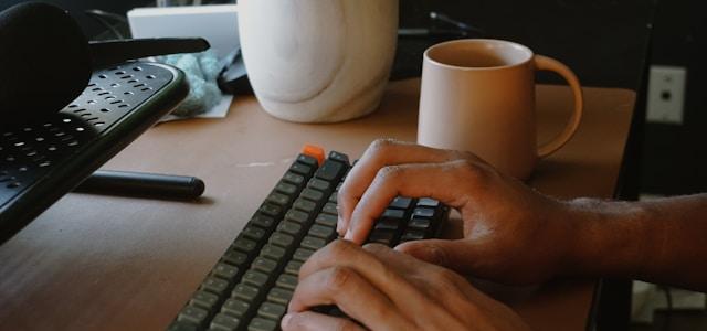 a person typing on a keyboard at a desk